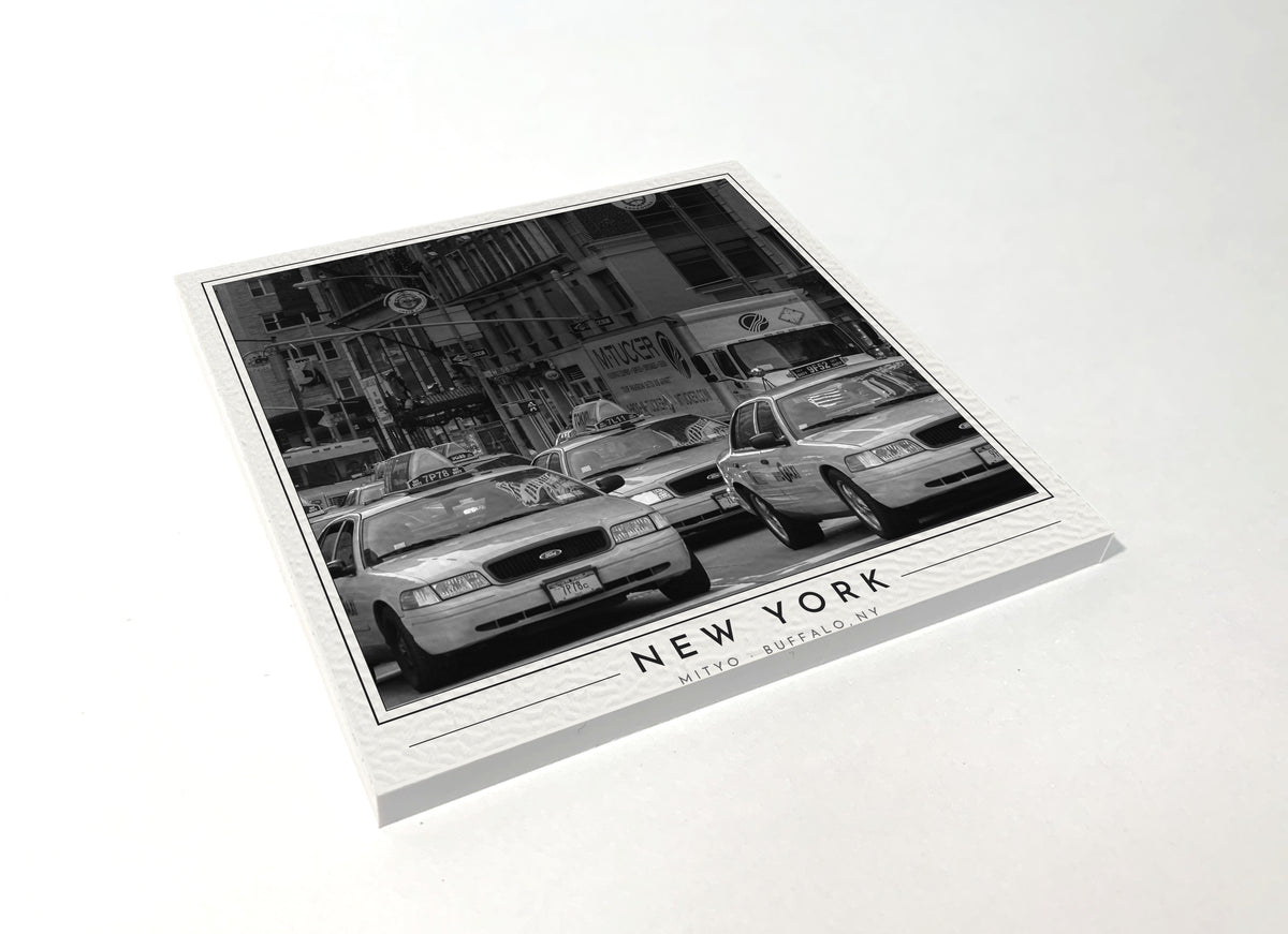 Square poster-style coaster of a line of yellow NYC taxi cabs, black-and-white
